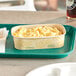 A World Centric rectangular compostable container filled with macaroni and cheese on a table.