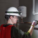 A woman wearing a hard hat and safety glasses using a PowerSmith LED headlamp to work on a pipe.