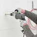 A person using a Genesis hammer drill to repair a wall.