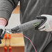 A person holding a Genesis Compact Mini Heat Gun with a curved nozzle.