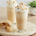 Two glasses of Frozen Bean hazelnut latte blended ice coffee with whipped cream and nuts.