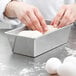 A person's hand kneading dough in a Chicago Metallic aluminized steel bread loaf pan.