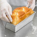 A person in gloves putting a loaf of bread in a Chicago Metallic bread loaf pan.