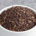 A bowl of Davidson's Organic Decaf English Breakfast loose leaf tea with brown leaves.