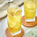 Two glasses of Davidson's Organic Lemon Ginseng Green Iced Tea with ice and lemon on a table.