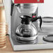 An Avantco coffee decanter with a stainless steel bottom and black handle on a counter.