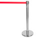 A silver metal Aarco crowd control stanchion with red retractable tape.