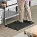 A man standing on a black anti-fatigue floor mat.