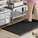 A man standing on a black Choice anti-fatigue floor mat in a kitchen.