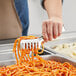 A person using Choice heavy weight stainless steel spaghetti tongs to serve themselves spaghetti.