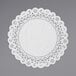 A white Lace Normandy doily on a gray surface.