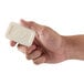 A hand holding a white bar of Dial White Marble Basics soap
