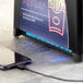 A cell phone charging in a Powers Paper black interfold napkin dispenser with a fast food restaurant on the screen.
