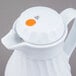 A white Vollrath SwirlServe tilt & pour coffee server with an orange button on top.