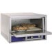 A Bakers Pride countertop pizza oven with pies baking in tin pans.