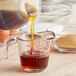 A person pouring Karo dark corn syrup into a measuring cup on a kitchen counter.