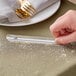 A person using a Choice aluminum pocket crumber to remove crumbs from a table.