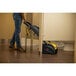 A person using a black and yellow Tornado Vortex walk behind floor scrubber to clean a floor.