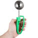 A hand holding a green tool with a round metal object.