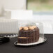 A chocolate cake in a Polar Pak plastic container with a dome lid on a table outdoors.