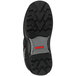 A close up of the cleated sole of a Tingley black work boot with a red logo.