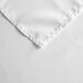 A close up of a white 100% polyester square table cover with a folded edge.