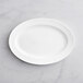 An Acopa Cordelia bright white porcelain oval platter on a white surface.