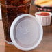 A Cambro translucent plastic lid with a straw slot on a glass of liquid.