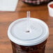 A translucent plastic Cambro lid with a straw slot on a Cambro tumbler with a straw in it.