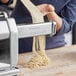 A woman using an Imperia pasta machine to make Capelli D'Angelo noodles.