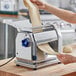A woman using an Imperia electric pasta machine to make dough.