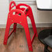 A red Koala Kare high chair sits in front of a table.