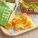 A sandwich with avocado and meat and Kettle Brand jalapeno potato chips on a tray.
