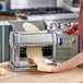 A woman using an Imperia stainless steel pasta machine to make pasta.