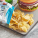 A bag of Cape Cod Sea Salt & Vinegar Kettle Cooked Potato Chips on a tray next to a burger.