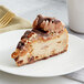 A slice of Eli's Totally Turtle Cheesecake with caramel and nuts on a plate.
