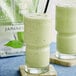 A glass of David Rio Tea Frost Japanese Matcha Frappe Mix, a green smoothie with a straw.
