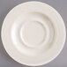 A close-up of a Homer Laughlin ivory saucer with a swirl design on a white background.