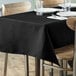 A table with a black tablecloth on it set with plates.