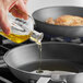 A person pouring Colavita Canola and Olive Oil blend into a frying pan.