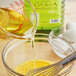 A bowl of eggs being whisked into liquid in a bowl on a kitchen counter with a bottle of Colavita Grapeseed Oil nearby.