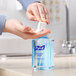 A person using a Purell Healthy Soap dispenser to apply white liquid to their hand.