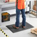 A person wearing blue jeans standing on a black Lavex anti-fatigue mat.