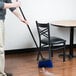 A person sweeping the floor with a Carlisle warehouse broom.