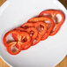 Sliced red bell peppers on a white plate using a Robot Coupe 3/16" slicing disc.