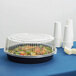A WNA Comet clear plastic container with a high dome lid over a salad.