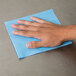 A hand using a blue Chicopee Veraclean wiper on a blue surface.