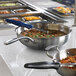 A Vollrath countertop induction warmer with a white ceramic template holding a pan of food.