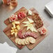 An Enjay wood laminated box filled with cheese, meat, and crackers on a table.