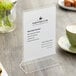 An acrylic Choice Tabletop Displayette holding a menu on a table.